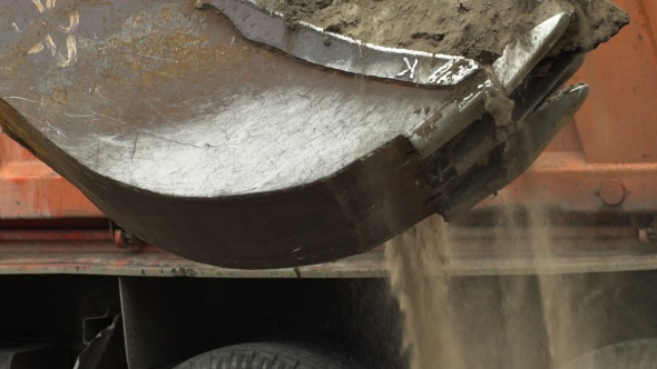 The Large Excavator Bucket Emptying The Land Under Load In The Truck.