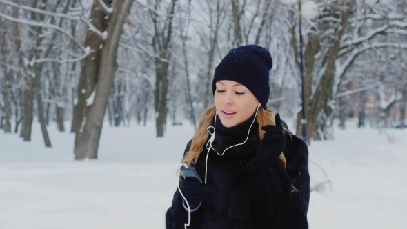 Winter Walk - Young Woman Walking In The Park, Listening To Music On Headphones, Around a Lot Of