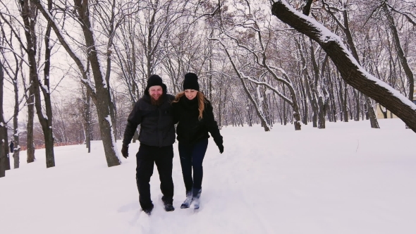 A Young Couple Moves Into The Winter Woods, Going Along a Narrow Path Through Deep Snow