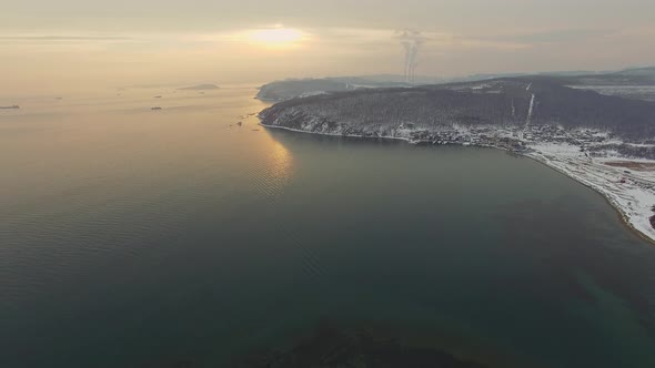 View From a Drone on a Snowcovered Rocky Seashore at Sunset