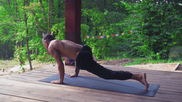 Man Performs Yoga Exercises, Lifting One Leg And Bending The Other.
