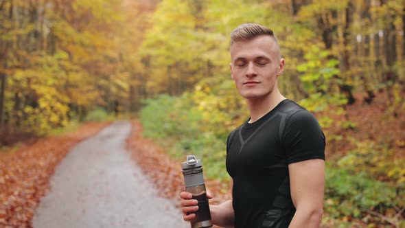 The Athlete is Standing on a Forest Road and Looking at the Camera