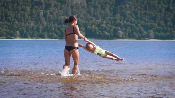 Mother Playing Turning Around Her Baby Girl Daughter In The Park Lake