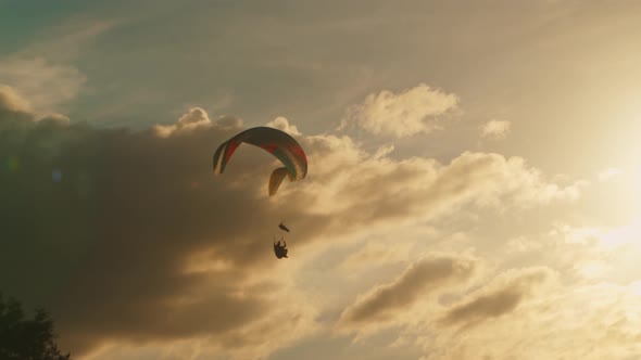 Two Paragliders Soar in a Beautiful Golden Sky Against the Sunset