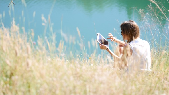 Girl Swiping On Tablet In Nature