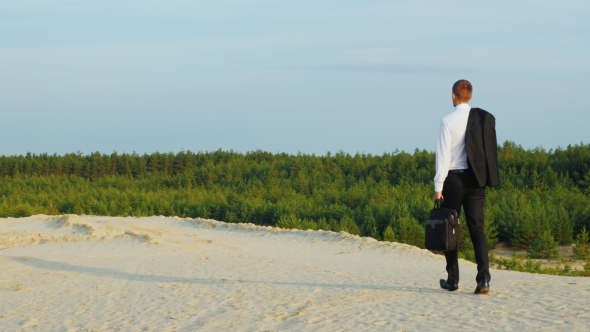 Carefree Businessman Walking On The Sand, Carries a Jacket Over His Shoulder. Back View