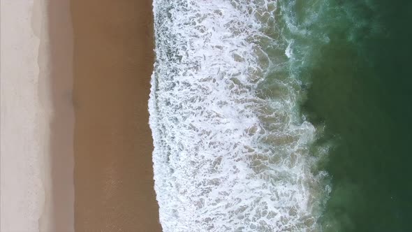 Aerial drone shot of waves crashing onto beach