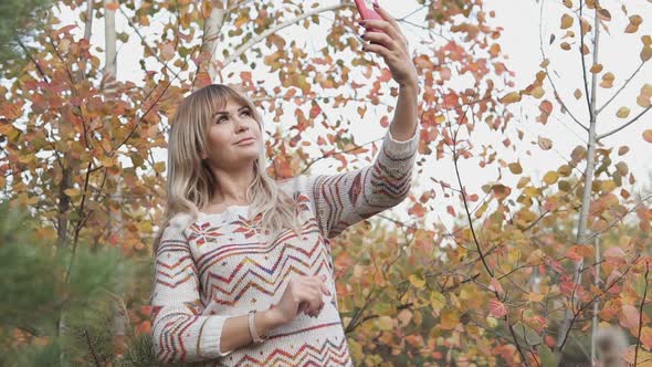 Blonde Girl Makes Selfie in the Autumn Park