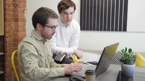 Two Men Working at Computer Sitting in Business Center Indoors