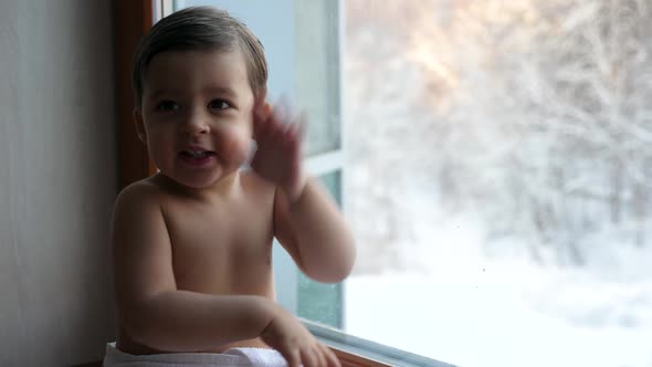 Little Baby Boy Sitting on Window in White Towel