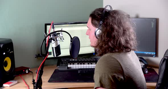 Young man wearing headphones and working from his broadcast studio speaking to the public