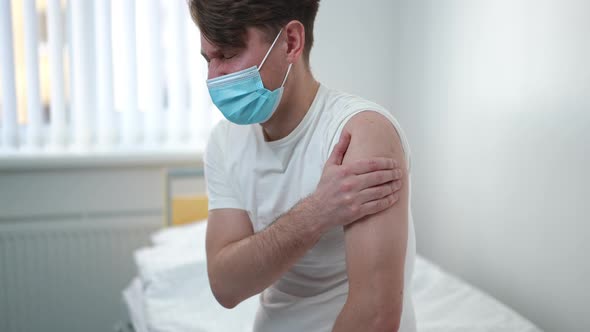 Side View Portrait of Sad Caucasian Man in Covid19 Face Mask with Medical Patch on Shoulder Sitting