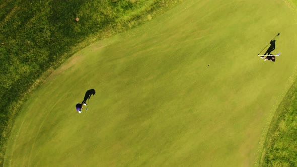 Aerial top-down over golfer hits ball rolling towards hole on putting green. Molndal near Gothenburg