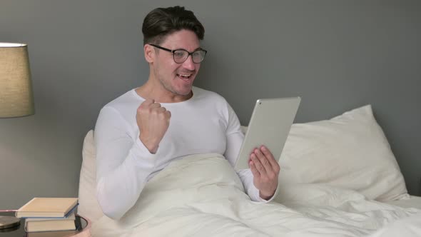 Excited Middle Aged Man Celebrating on Tablet in Bed 