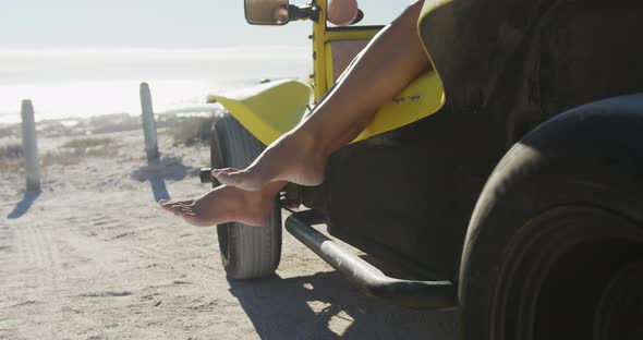 Happy caucasian woman sitting in beach buggy by the sea