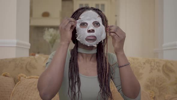 Portrait of Cute Beautiful African American Woman Putting Moisturizing Facial Mask on Her Face on