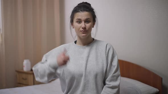 Portrait of Distracted Woman in Video Chat Gesturing Thumb Up with Surprised Facial Expression