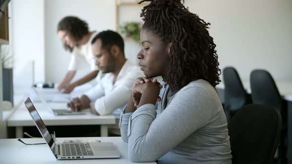 Sad Young Woman Leaning on Hands and Looking at Laptop