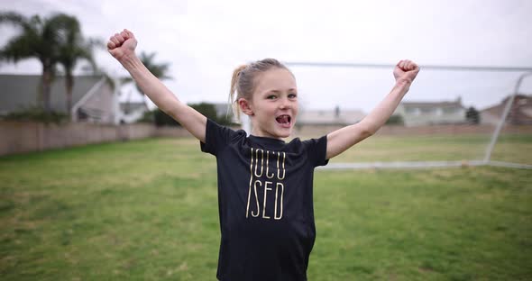 A young athletic girl flexes her muscles and smiles for the camera.