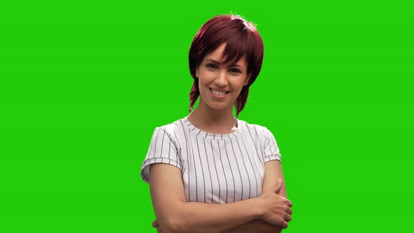 Beautiful smiling woman posing on green screen with arms crossed