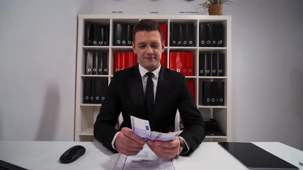 Young Handsome Business Man in Black Suit and Tie Counting Euro
