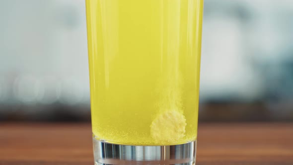 Effervescent Tablet Vitamin C Nutritional Supplements in Glass with Yellow Carbonated Water Sport