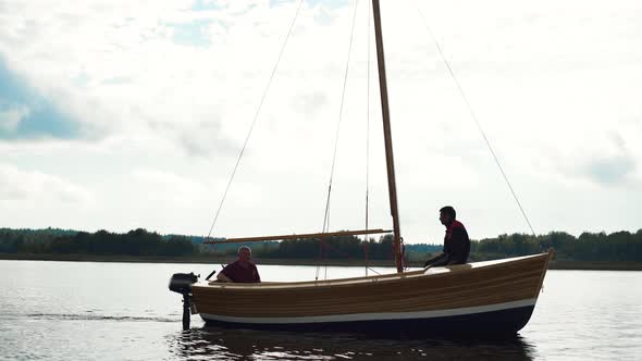 Master and His Assistant Working at Wood Sailboat on River with Mast