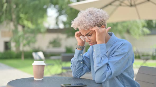 Young African Woman with Coffee Having Headache in Outdoor Cafe