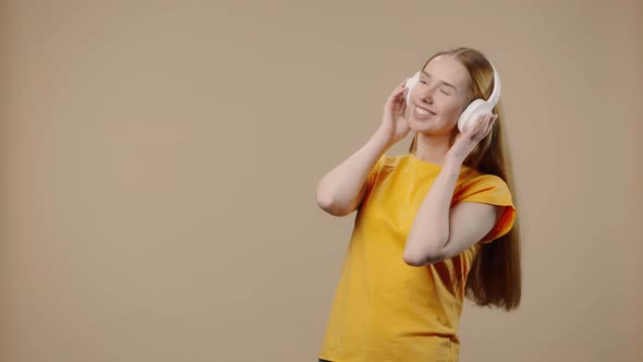 Portrait of Model with Natural Beauty Enjoying Music in Big White Headphones