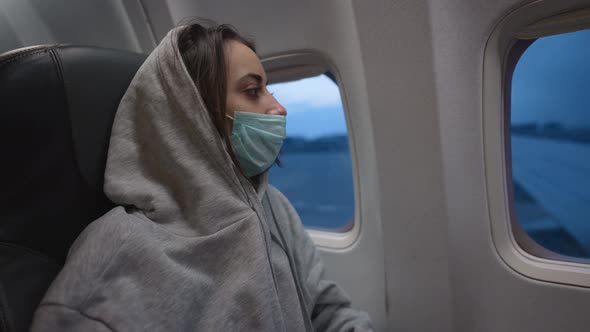 Woman in Hoodie and Medical Mask in Airplane Cabin