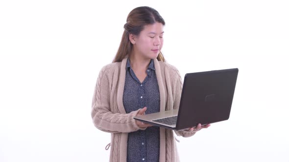 Happy Young Asian Woman Talking While Using Laptop Ready for Winter