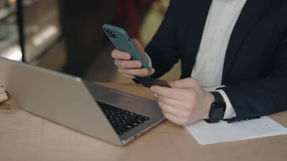 Businessman Typing Credit Card Number on Mobile Phone Buying Items