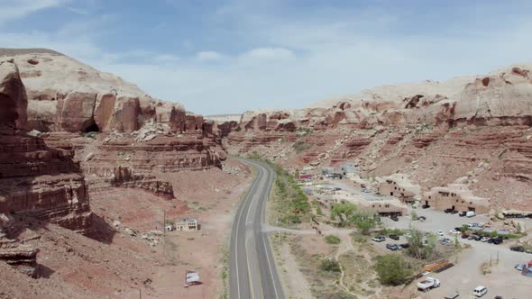 Aerial View Of Isolated Asphalt Road Along Towering Red Sandstone Cliffs In Bluff, Utah USA.