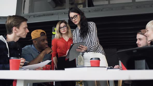 Young Businesswoman Presenting New Business Plan to Here Young Hipster Team