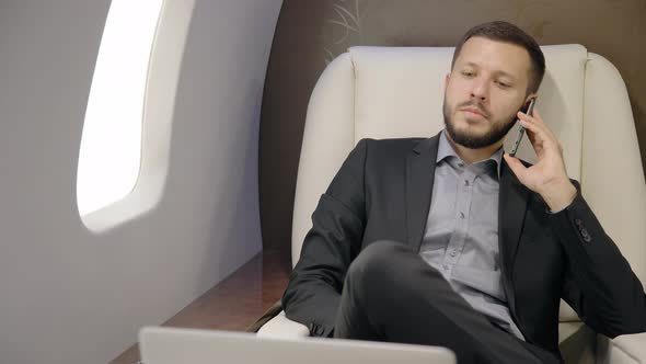 Portrait of Male Businessman Talking on Phone in His Private Plane.