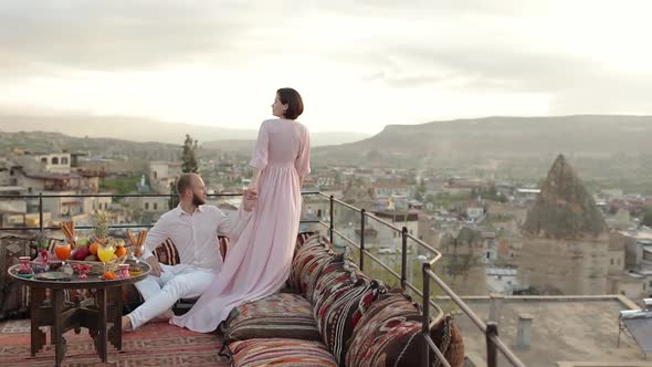 Woman and men sitting on the top of the roof and enjoys the morning view on Goreme park, Cappadocia