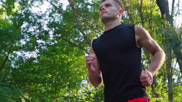 Young Man Jogging Under Trees in Slow Motion