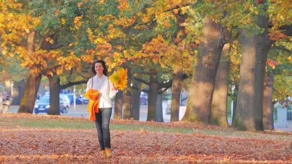 Happy Attractive Woman with Autumn Leaves Walking in Park