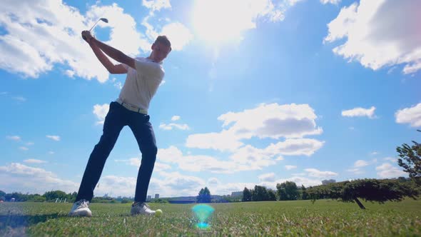 Male Golfer Hits a Ball on a Course While Training.