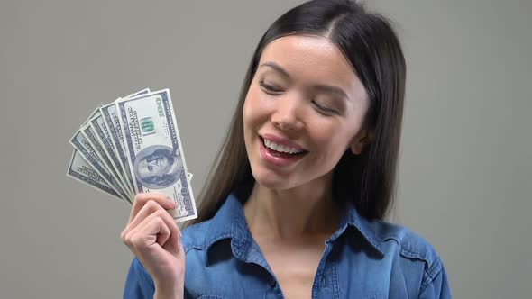 Pensive Asian Lady Looking at Bunch of Euros, Thinking About Shopping, Close Up