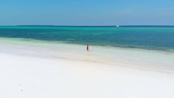 Aerial slow motion: woman walking on tropical beach, scenic turquoise sea