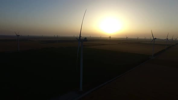 Wind Turbines in Wheat Fields in Summer at Sunset. Silhouette. Aerial Survey