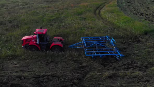 Red tractor with blue plow