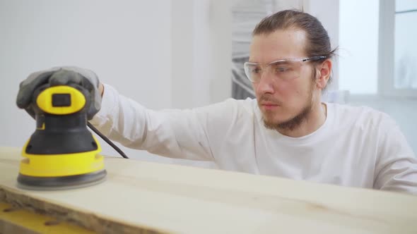 Carpenter in Protective Gloves and Glasses for Working on Wood Grinding Machine