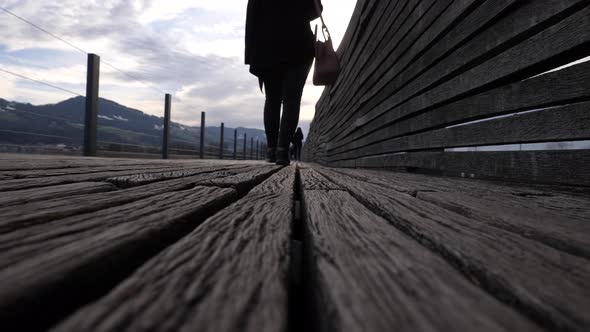 Lockdown low angle shot of a young asian woman walking on a wooden pier in Slow motion.