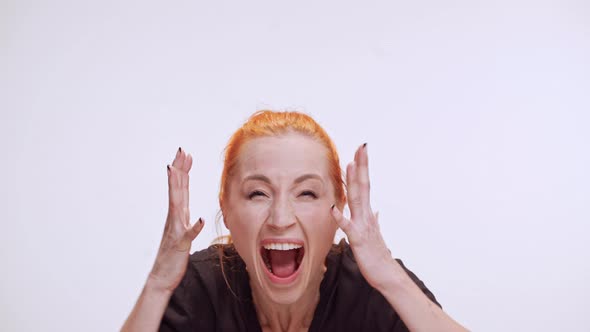 Very Angry Middleaged Caucasian Female with Colored Orange Hair Screaming at Camera Holding Hands