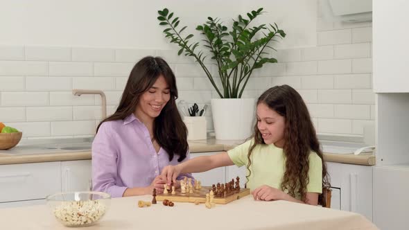 Cheerful Daughter Wins Mom in Chess While Sitting at the Kitchen Table