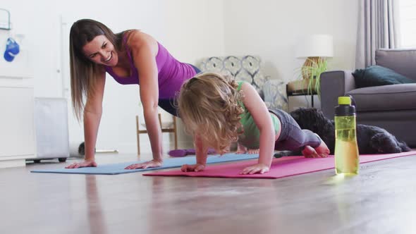 Caucasian mother and daughter practising yoga in living room