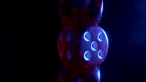 Red Dice Spinning on an Isolated Black Background Illuminated By Blue Light