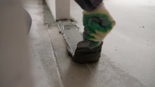 A Builder Applies Glue to Build a Wall of Aerated Concrete Blocks